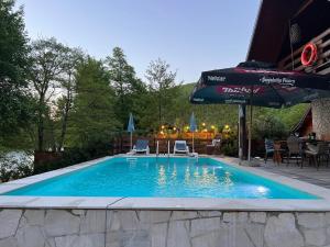 a swimming pool with an umbrella and chairs and a table at Property with your own beach and pool - Whispering Waters in Krupa na Vrbasu