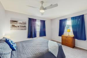 a bedroom with blue curtains and a bed and a dresser at Mangrove View on Oyster Creek in Englewood +28 photos