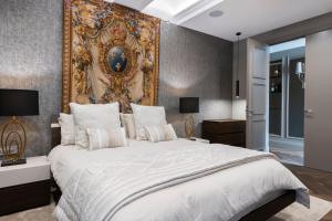 バレッタにあるLux Top Floor in the Hearth of Valletta by ArcoBnbの壁に絵が飾られた大きなベッドのある寝室