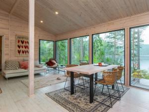 a dining room with a table and chairs and windows at Holiday Home Sarppala by Interhome in Putkijärvi