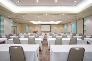 a conference room with white tables and chairs and a screen at Hotel Precede Koriyama in Koriyama