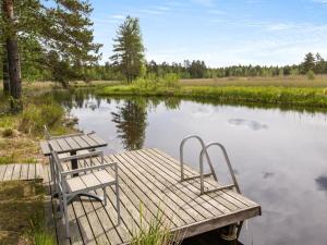 a wooden dock with two chairs on a lake at Holiday Home Mustijoki by Interhome in Savitaipale