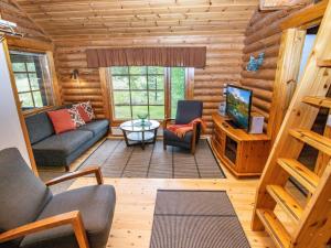 a living room with a couch and a tv in a log cabin at Holiday Home Mustijoki by Interhome in Savitaipale