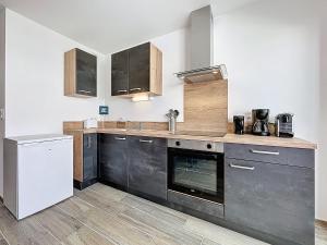 a kitchen with black cabinets and a white refrigerator at Apartment Océanide-2 by Interhome in La Bernerie-en-Retz