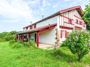 Una casa blanca con detalles rojos sobre un campo verde. en Apartment Iratzea by Interhome, en Saint-Pée-sur-Nivelle