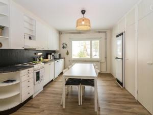une cuisine avec des armoires blanches, une table et une fenêtre dans l'établissement Holiday Home Kalamiehenkatu 6 by Interhome, à Kemi