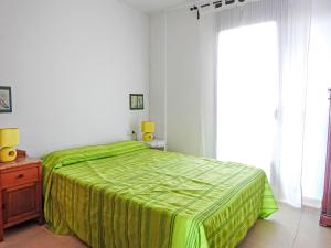 a bedroom with a green bed and a window at Apartment La Platja by Interhome in L'Estartit