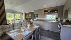 a kitchen with a wooden table and a counter top at Bowness Retreats FallBarrow Park in Bowness-on-Windermere