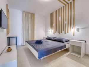 a white bedroom with a bed and a television at Apartment Dita-1 by Interhome in Crikvenica