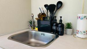 a kitchen counter with a sink and a container of utensils at LAC Holiday Apartment in Calceranica al Lago +25 photos