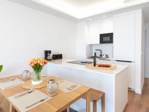 a white kitchen with a wooden table and a counter at Apartment D'Mediterranea private pool & sauna by Interhome in Torrox Costa