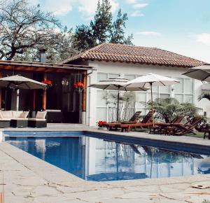 a swimming pool with umbrellas and chairs and a house at Finca Catalina Hotel Boutique in Tepoztlán