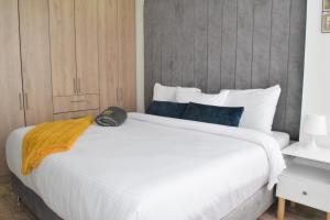 a large white bed with a yellow blanket on it at Apartamento nuevo a 7 min de la Escuela de Cadetes in Bogotá