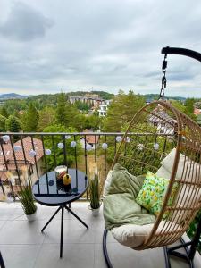a porch with a swinging chair and a table at Apartman Njegoš Lux Titova vila in Palisad