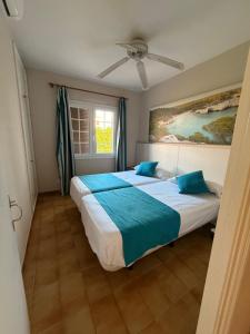 a bedroom with two beds and a ceiling fan at Siestamar II in Cala'n Porter