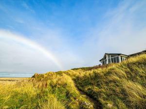 a house on top of a hill with a rainbow at Holiday Home Waters Edge by Interhome in Lossiemouth