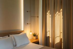 ein Schlafzimmer mit einem Bett mit weißen Laken und einem Fenster in der Unterkunft Agia Sofia 21 Suites - Smooth Living in Thessaloniki