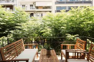 einen Balkon mit zwei Bänken und einem Tisch mit einer Pflanze in der Unterkunft Agia Sofia 21 Suites - Smooth Living in Thessaloniki