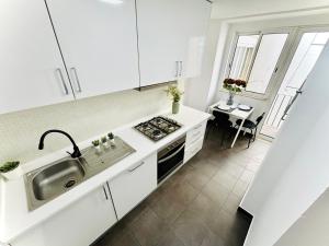 a white kitchen with a sink and a stove at Luxury rooms, Lisbon city centre in Lisbon