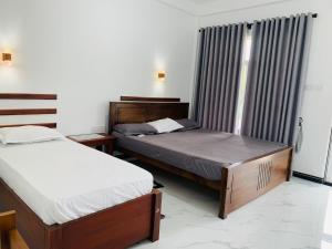 Un dormitorio con dos camas y una ventana en White Shine Hotel, en Polonnaruwa