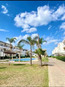 a resort with palm trees and a swimming pool at Appartement marbella beach in Mansouria