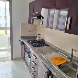 a kitchen with a sink and a stove top oven at Appartement marbella beach in Mansouria