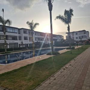 a building with palm trees next to a body of water at Appartement marbella beach in Mansouria