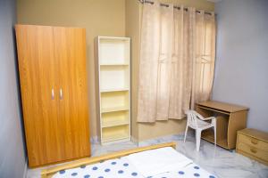 Un dormitorio con una cama, un escritorio y un armario. en Eliogemi Guest Room, en Gbawe