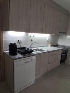 a kitchen with a sink and a dishwasher at Casa Rainha Amélia in Monte Gordo