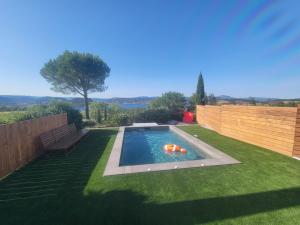 a swimming pool in a yard with a wooden fence at VillaT5 Piscine vue Lac du Salagou in Liausson