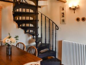 a dining room with a table and a spiral staircase at Honeysuckle Cottage in Great Yarmouth