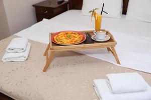 a tray with a pizza on a table on a bed at DOWNTOWN ROOMS in Niš