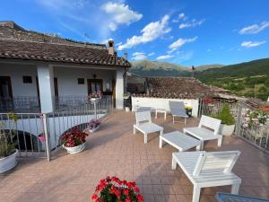 a patio with white chairs and a house at Piazzetta Del Forno - Monolocale in Assergi +27 photos