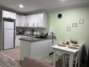 a kitchen with white cabinets and a table with chairs at Çınar Grup Suit in Fethiye