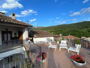 a balcony of a house with white chairs and flowers at Piazzetta Del Forno - Monolocale in Assergi