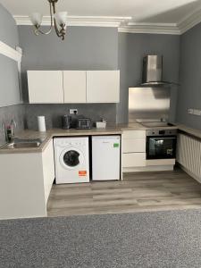 a kitchen with white cabinets and a washer and dryer at Regent Hotel in Eastbourne