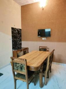 a dining room table with chairs and a tv on the wall at Elegant & Spacious Venue in Kota +13 photos