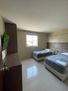a bedroom with two beds and a flat screen tv at Apto Grand- Ithiel in Barranquilla