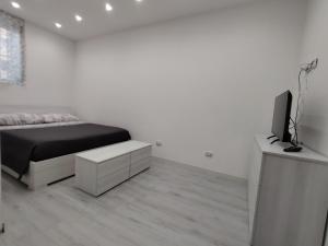 a white bedroom with a bed and a tv at La Casetta di Nonno Settimo in Palermo