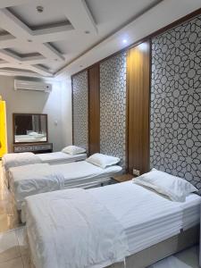 a hotel room with three beds and a tv at المحرق للشقق المخدومة in Al Hofuf
