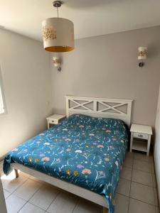 a bedroom with a bed with a blue comforter at Beauséjour près du golf in Cabriès