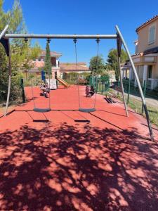 a playground with swings in a park at Beauséjour près du golf in Cabriès