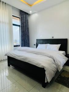 a bedroom with a large bed with a large window at The Luxe Urban Lounge in Kigali