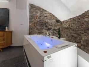 a bathroom with a tub with a tv and a stone wall at Royal Suite Spa et Balnéo Privatif in Lyon +29 photos