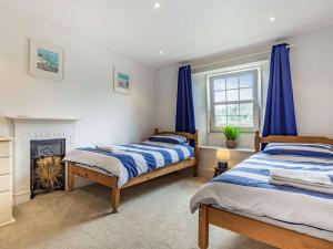 two beds in a bedroom with blue curtains and a fireplace at 4 Bed in Lerryn 51028 in Lerryn
