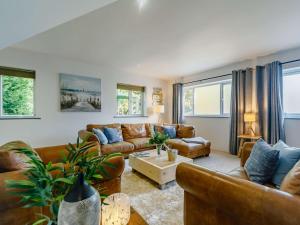 a living room with brown leather furniture and windows at 3 Bed in Portreath 89492 in Camborne