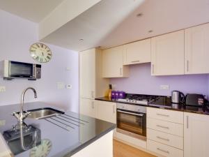 a kitchen with white cabinets and a clock on the wall at 2 Bed in Fort Augustus 80700 in Fort Augustus