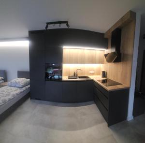 eine Küche mit schwarzen Schränken und einer Spüle und einem Bett in der Unterkunft Apart Family Lębork in Lębork
