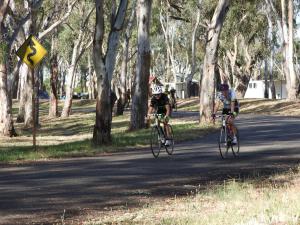 a man riding a bike down a road next to trees at Victoria Lake Holiday Park in Shepparton