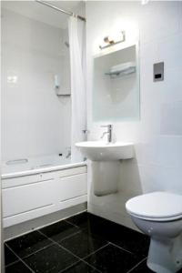 a white bathroom with a toilet and a sink at Artto Hotel in Glasgow